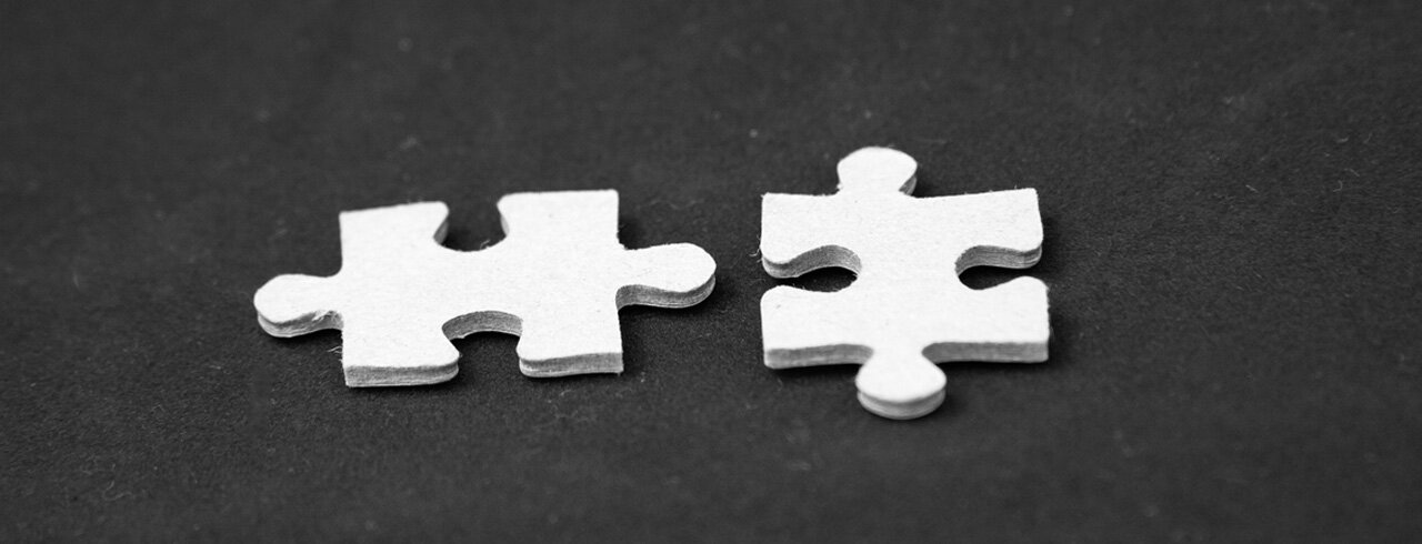 Two white puzzle pieces on a dark background